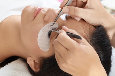 Woman undergoing lash extensions procedure in beauty salon, closeup