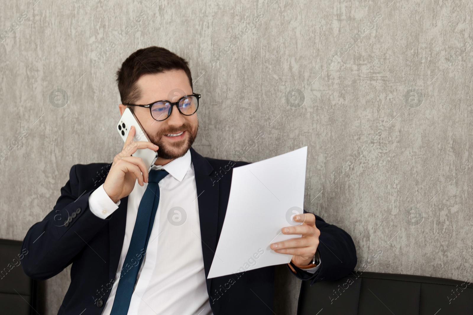 Photo of Banker with document talking on smartphone in office