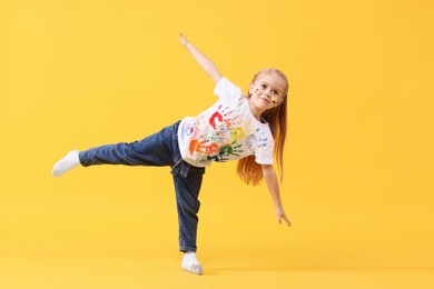 Photo of Cute girl smeared in paint on orange background