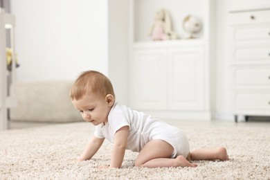 Photo of Adorable baby crawling on floor in nursery