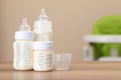 Photo of Feeding bottles with milk on wooden table indoors, space for text