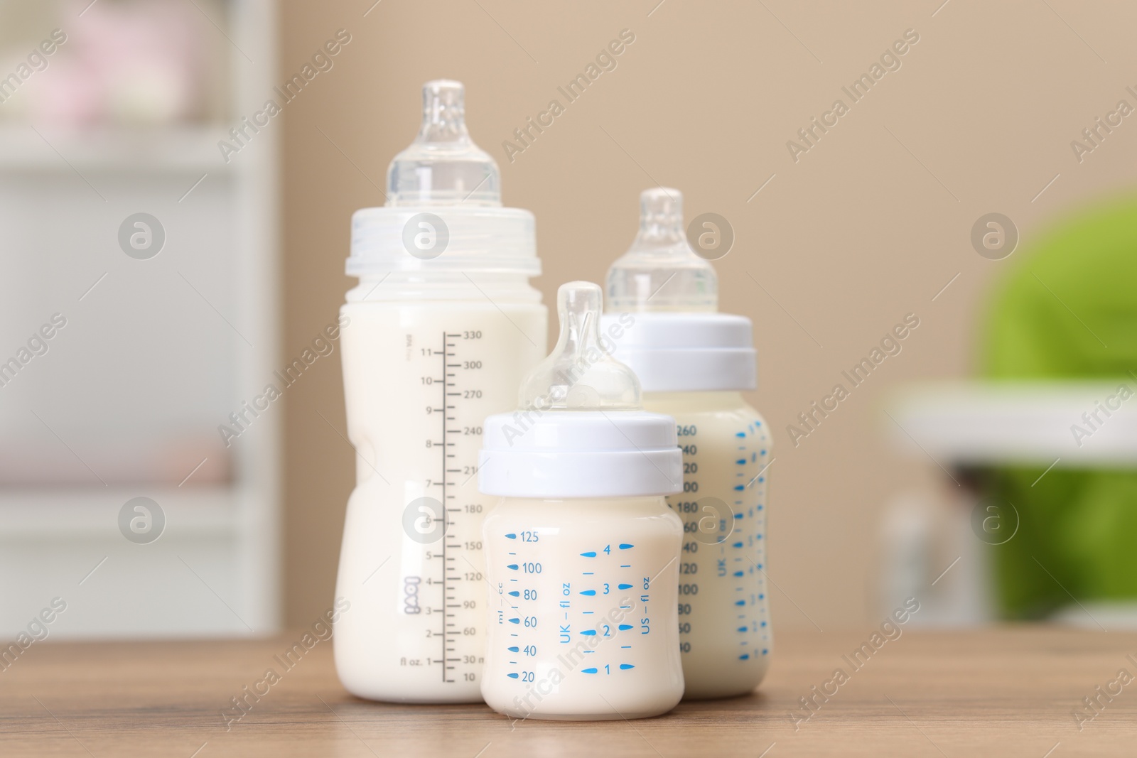 Photo of Feeding bottles with milk on wooden table indoors