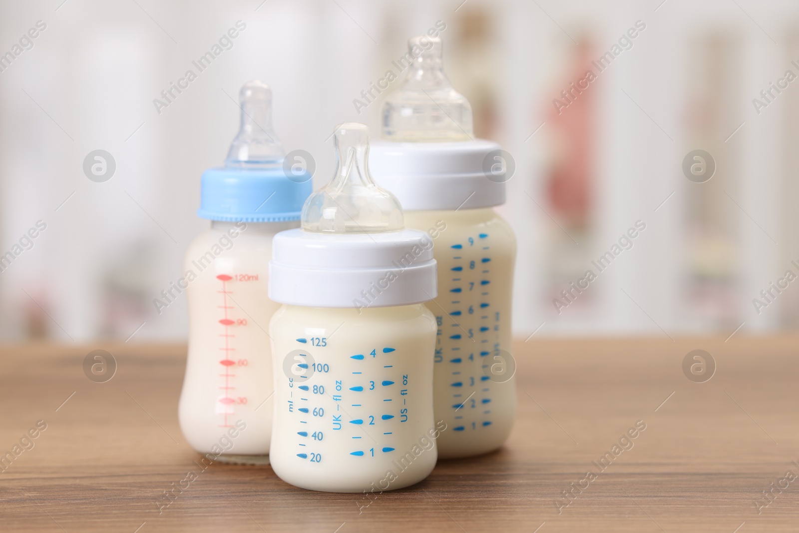 Photo of Feeding bottles with milk on wooden table indoors