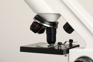 Science. Microscope with glass slide on light grey background, closeup