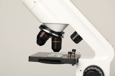 Science. Microscope with glass slide on light grey background, closeup