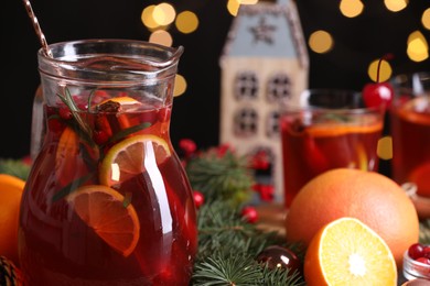 Photo of Tasty punch drink in glass jug and Christmas decor on table, closeup