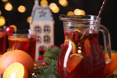 Photo of Tasty punch drink in glass jug and Christmas decor on table, closeup