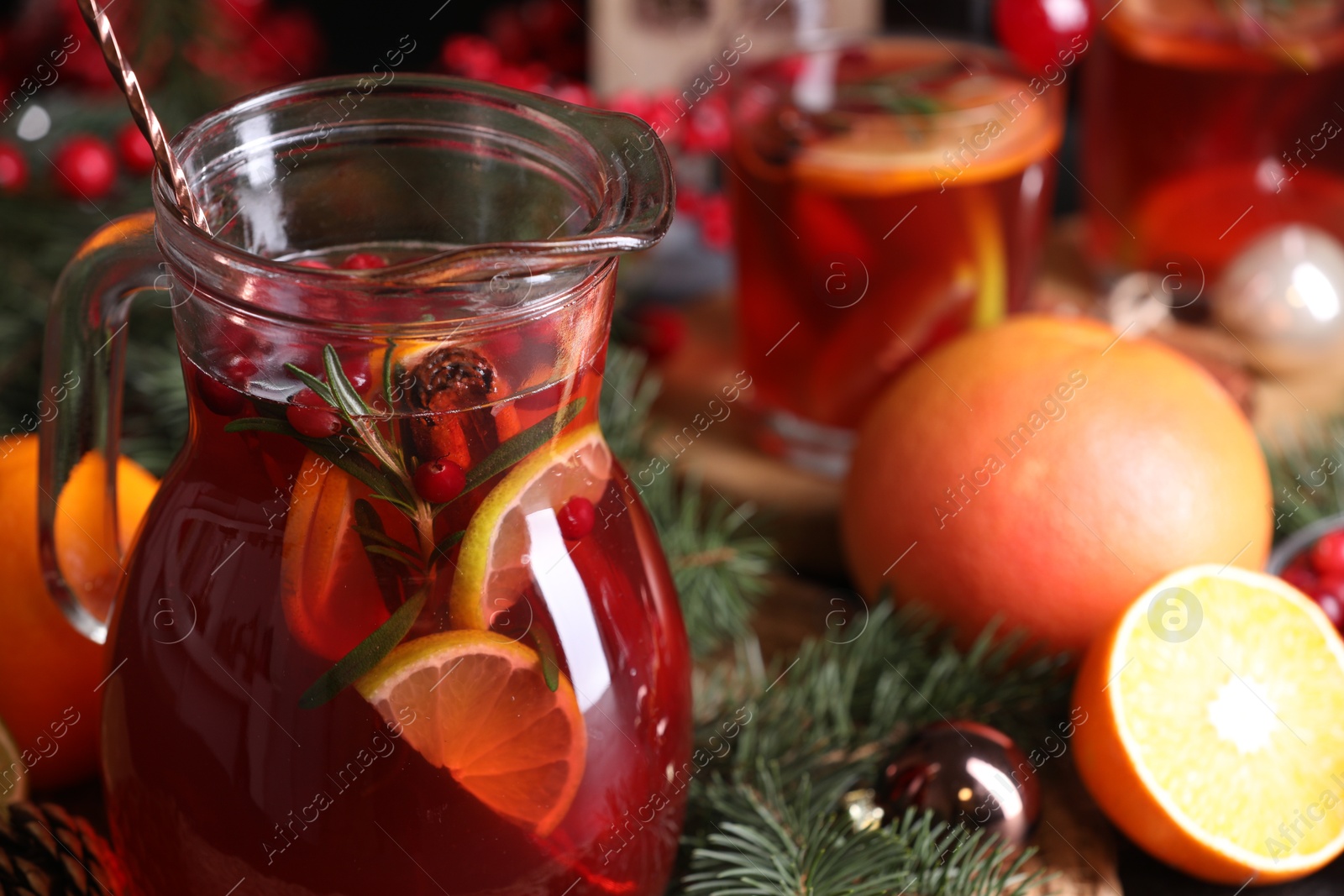 Photo of Tasty punch drink in glass jug and Christmas decor on table, closeup