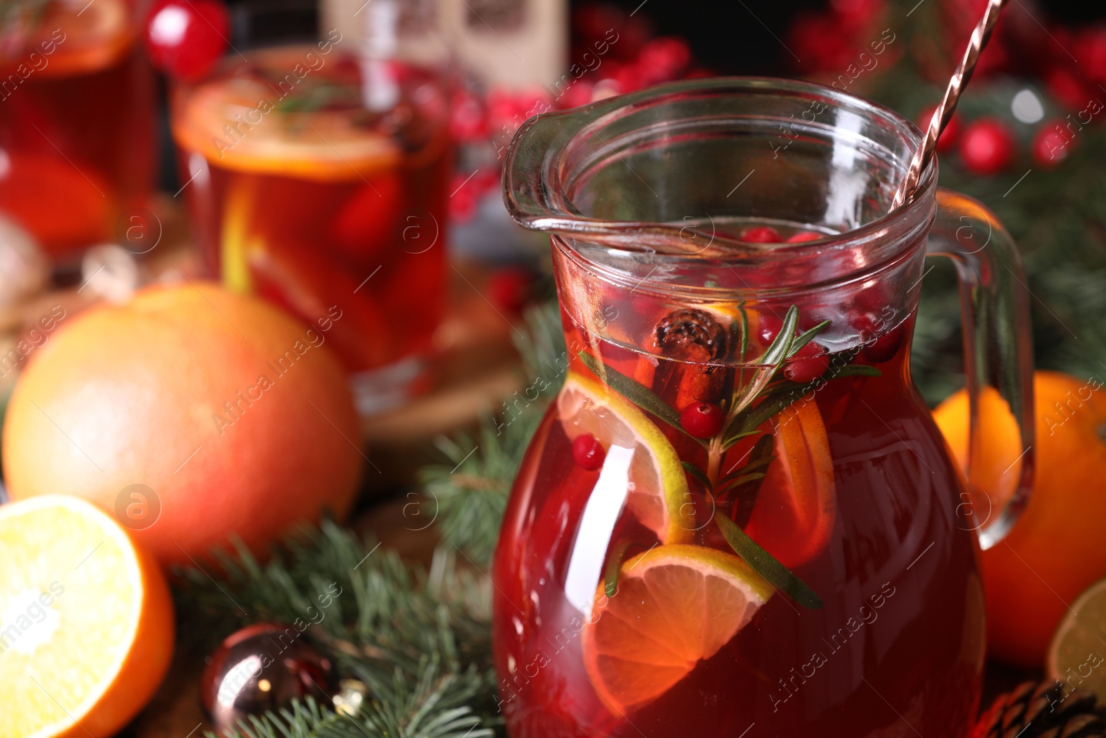 Photo of Tasty punch drink in glass jug and Christmas decor on table, closeup