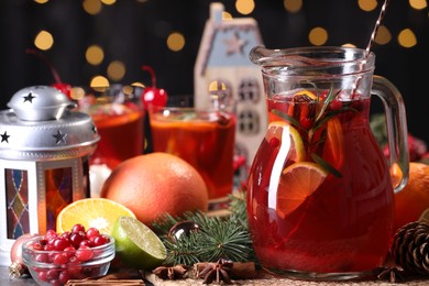 Photo of Tasty punch drink in glass jug, ingredients and Christmas decor on table