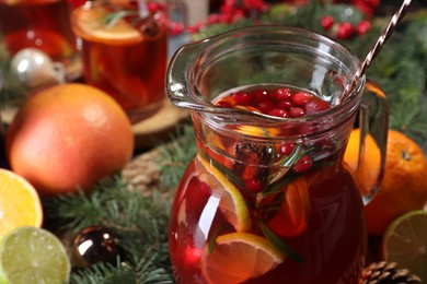 Photo of Tasty punch drink in glass jug, ingredients and Christmas decor on table, closeup