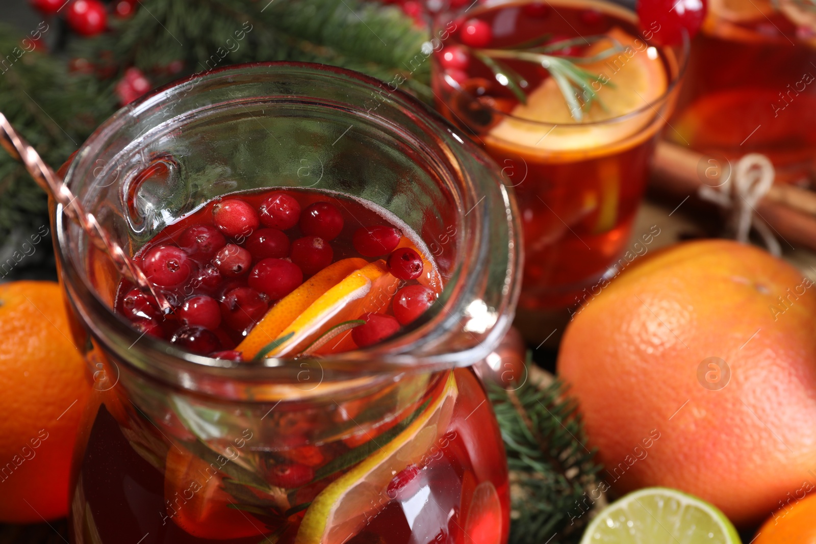 Photo of Tasty punch drink in glass jug and ingredients on table, closeup