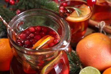 Photo of Tasty punch drink in glass jug and ingredients on table, closeup