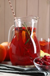 Photo of Tasty punch drink in glass jug and ingredients on table, closeup