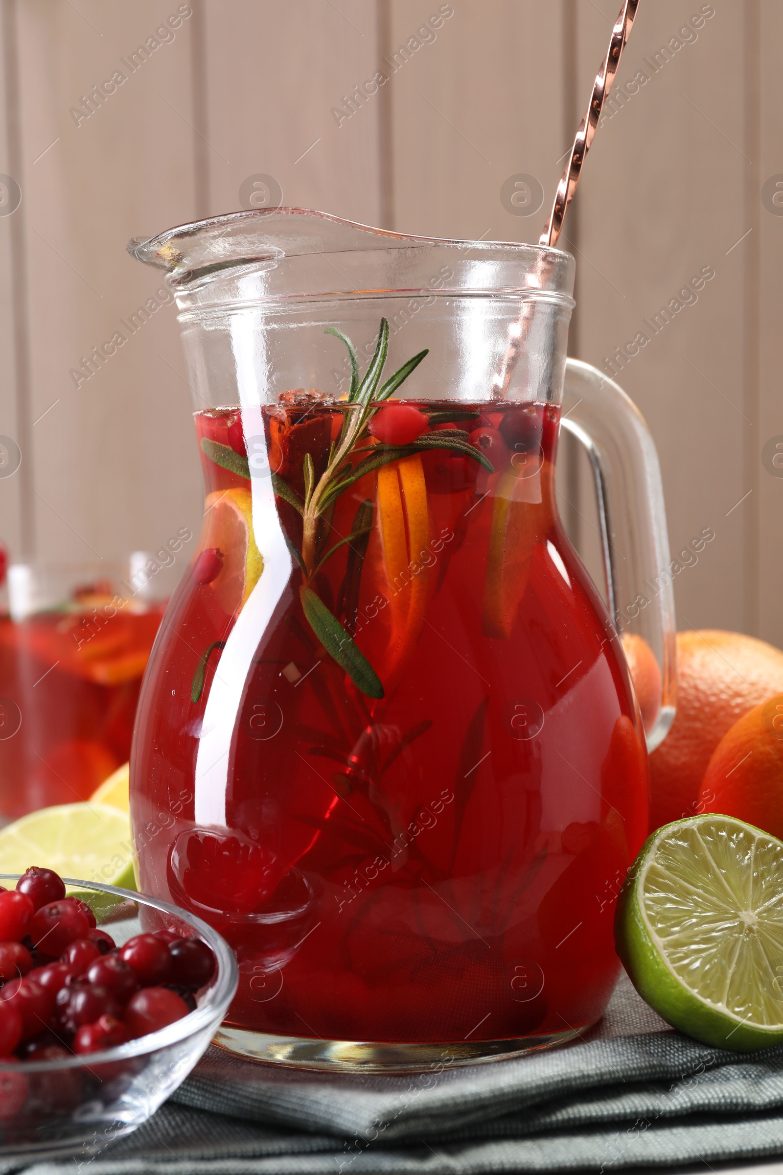 Photo of Tasty punch drink in glass jug and ingredients on table, closeup