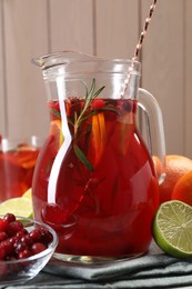 Photo of Tasty punch drink in glass jug and ingredients on table, closeup