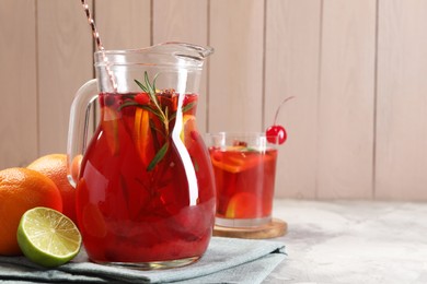 Photo of Tasty punch drink and ingredients on white table, space for text