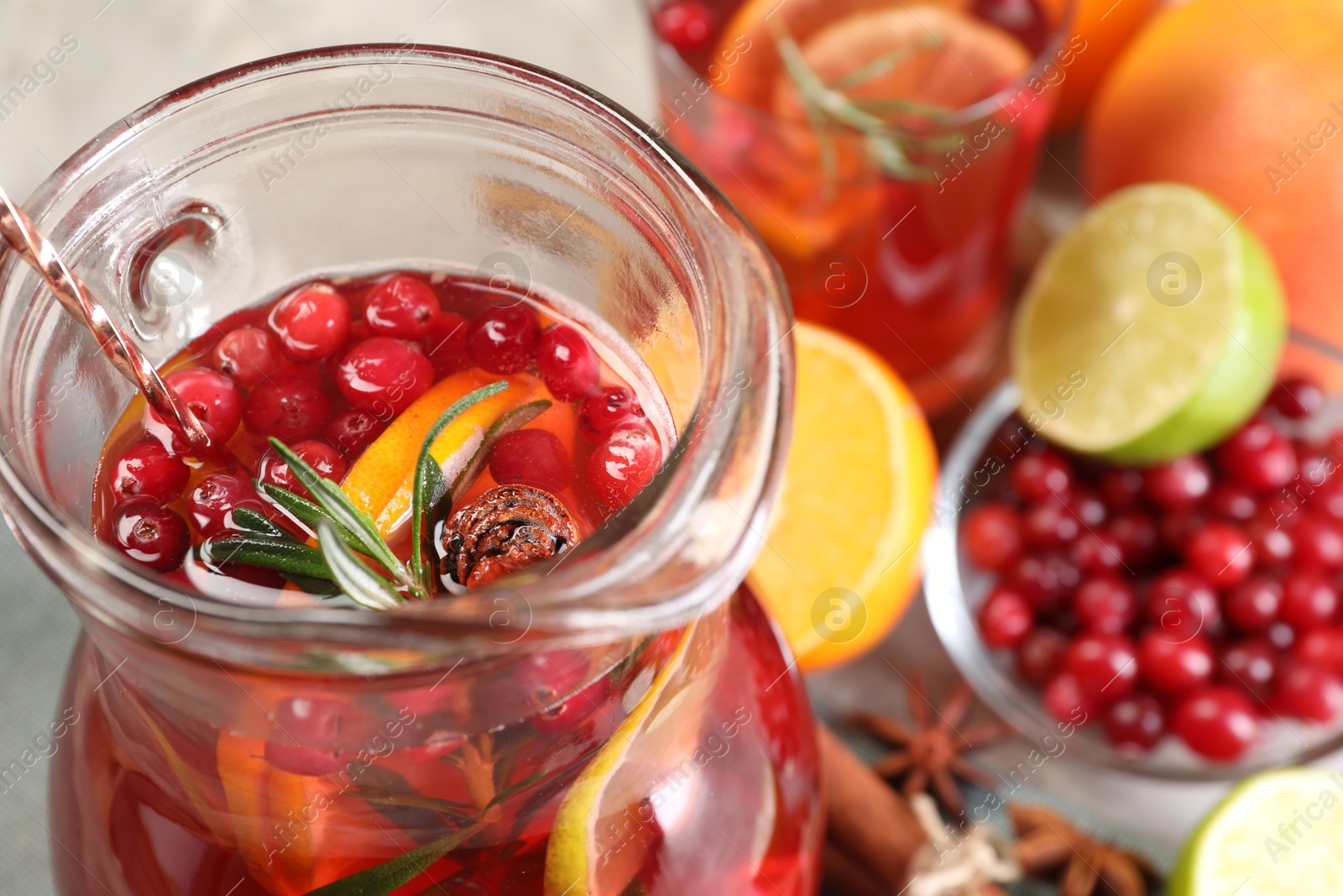 Photo of Tasty punch drink in glass jug and ingredients on table, closeup