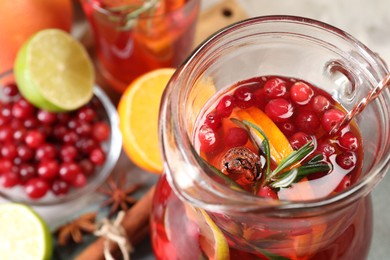 Photo of Tasty punch drink in glass jug and ingredients on table, closeup