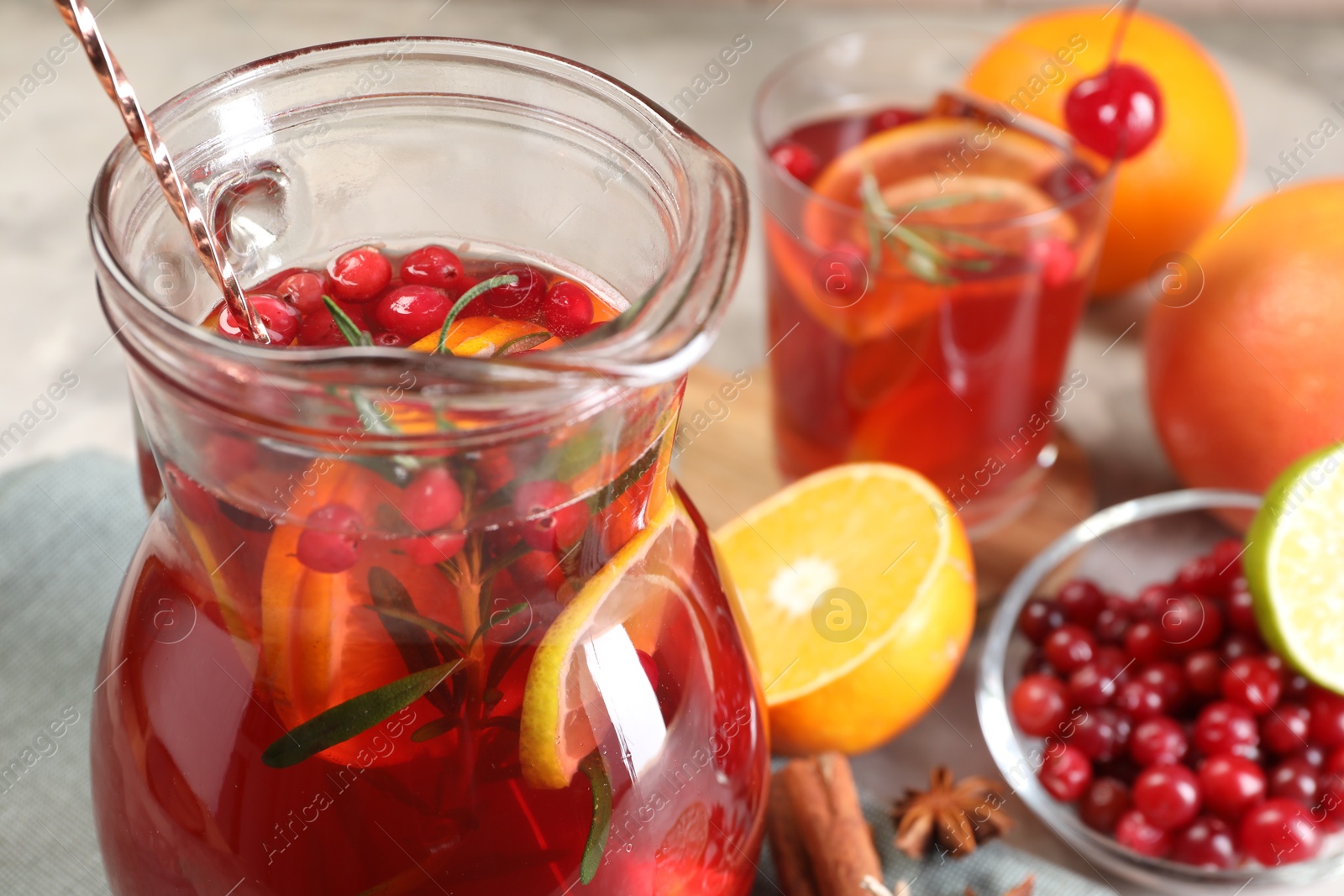 Photo of Tasty punch drink in glass jug and ingredients on table, closeup