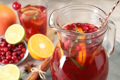 Photo of Tasty punch drink in glass jug and ingredients on table, closeup