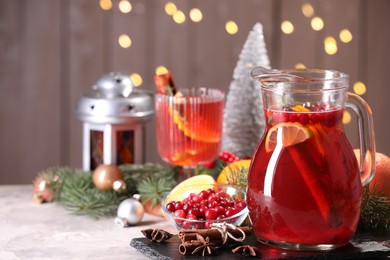 Photo of Tasty punch drink in glass jug, ingredients and Christmas decor on white table, space for text