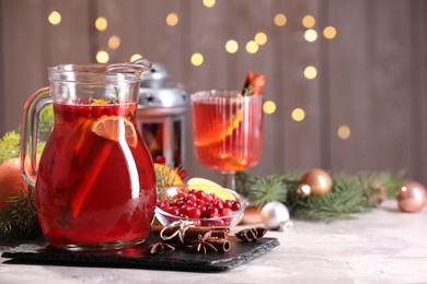 Photo of Tasty punch drink in glass jug, ingredients and Christmas decor on white table, space for text