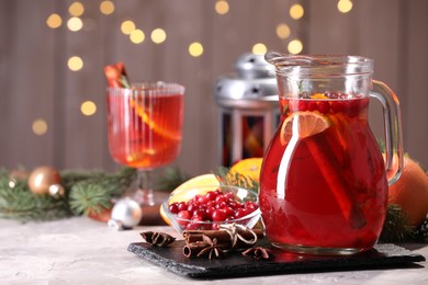 Photo of Tasty punch drink in glass jug, ingredients and Christmas decor on white table, space for text