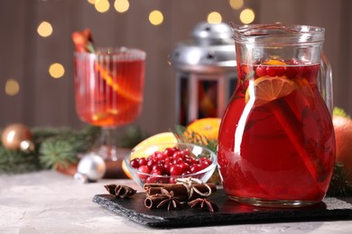 Photo of Tasty punch drink in glass jug, ingredients and Christmas decor on white table