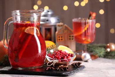 Photo of Tasty punch drink in glass jug, ingredients and Christmas decor on white table, space for text