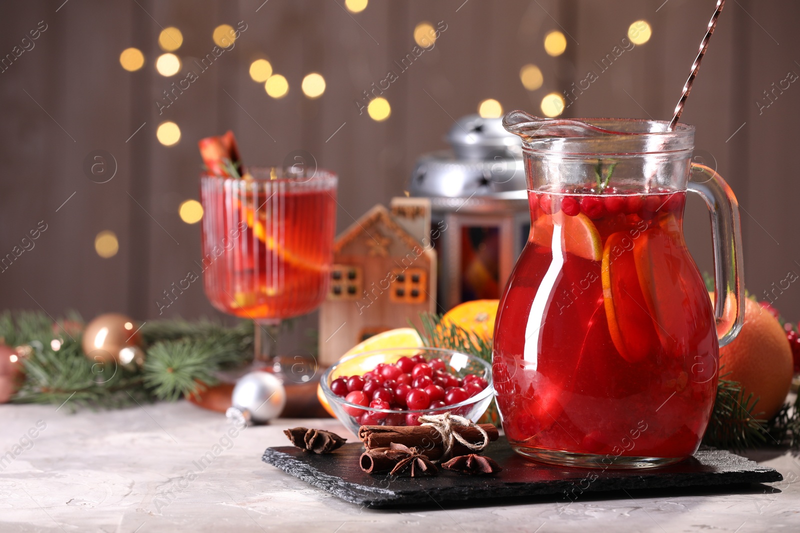 Photo of Tasty punch drink in glass jug, ingredients and Christmas decor on white table, space for text