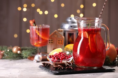 Photo of Tasty punch drink in glass jug, ingredients and Christmas decor on white table, space for text