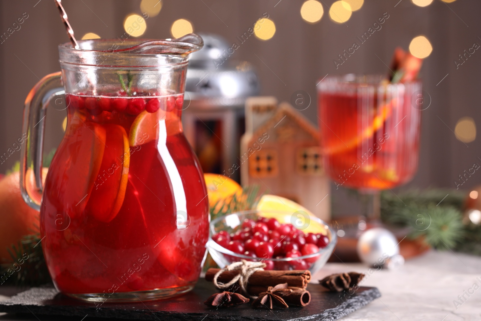 Photo of Tasty punch drink in glass jug, ingredients and Christmas decor on white table, space for text