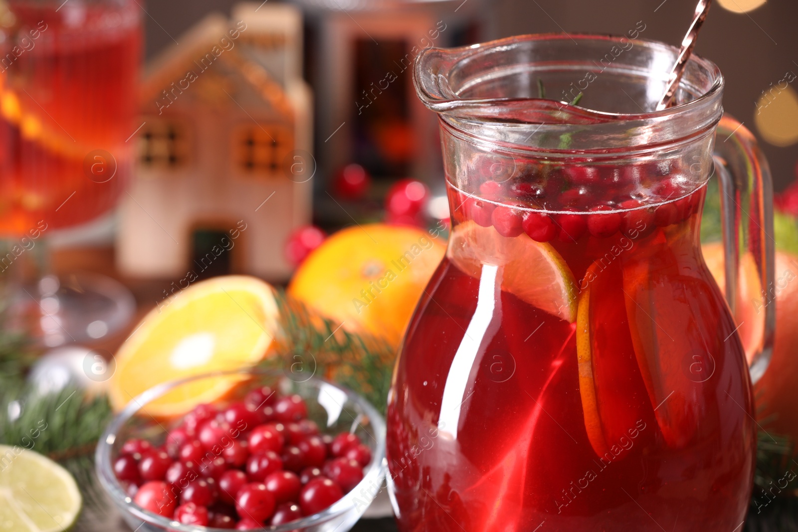 Photo of Tasty punch drink in glass jug, ingredients and Christmas decor on table, closeup