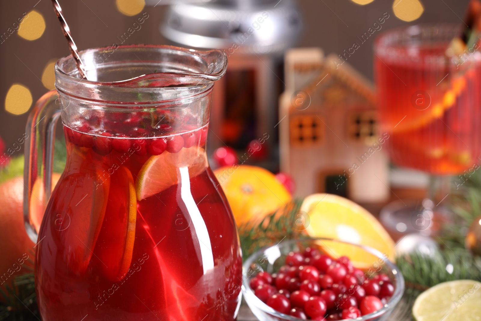 Photo of Tasty punch drink in glass jug, ingredients and Christmas decor on table, closeup