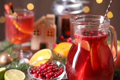 Photo of Tasty punch drink in glass jug, ingredients and Christmas decor on table, closeup