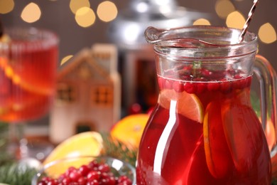 Photo of Tasty punch drink in glass jug, ingredients and Christmas decor on table, closeup