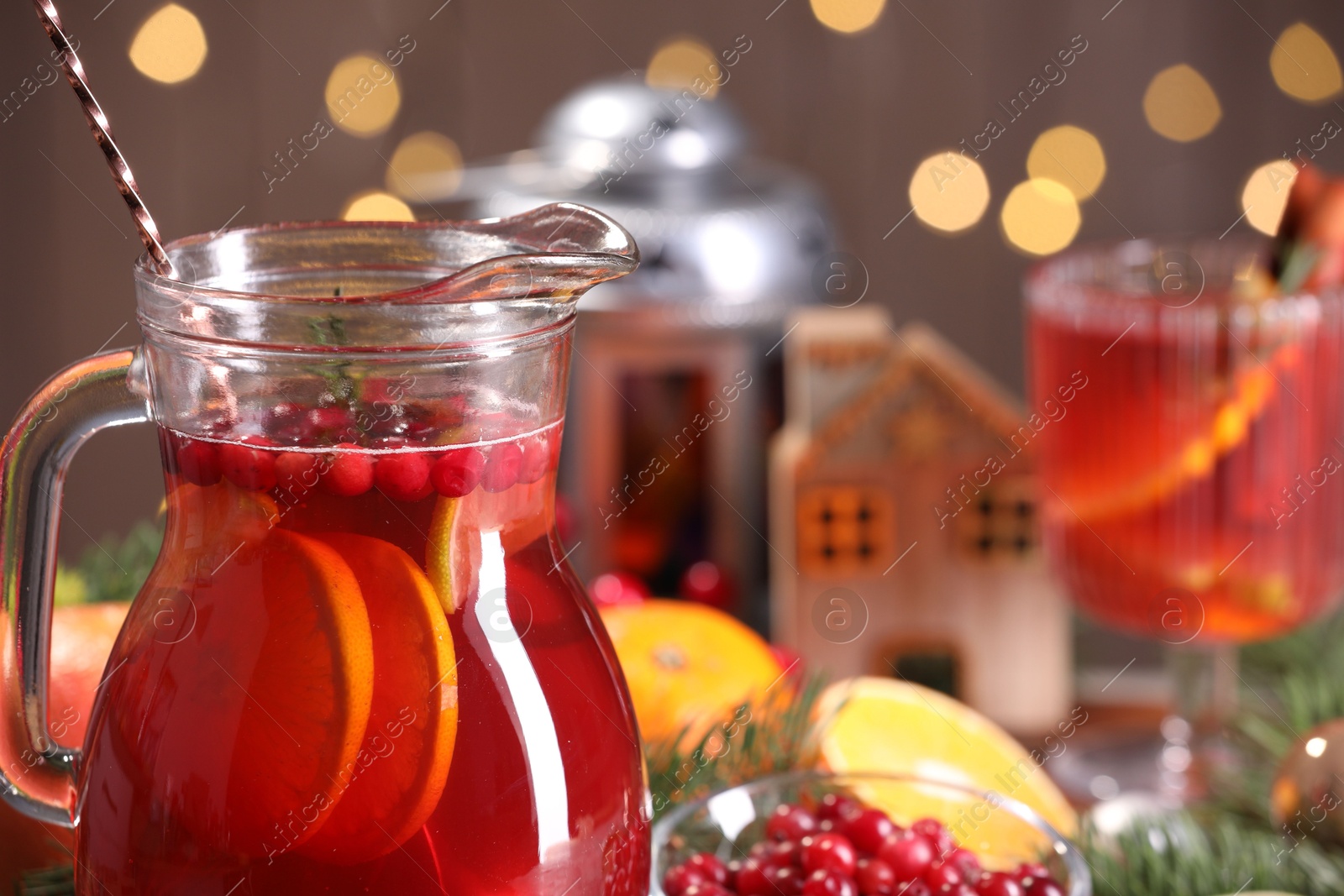 Photo of Tasty punch drink in glass jug, ingredients and Christmas decor on table, closeup