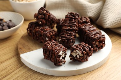 Photo of Delicious chocolate puffed rice bars on wooden table, closeup