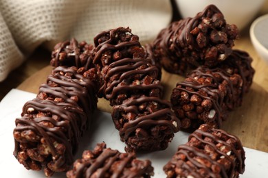 Delicious chocolate puffed rice bars on wooden table, closeup