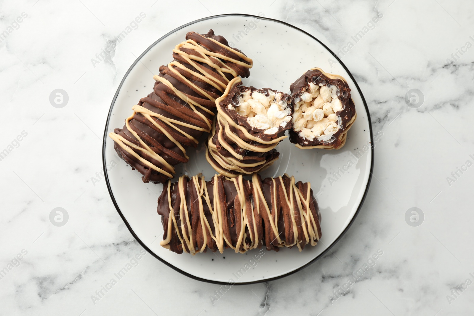 Photo of Delicious chocolate puffed rice bars on white marble table, top view