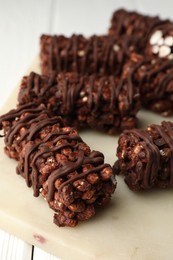 Delicious chocolate puffed rice bars on white wooden table, closeup