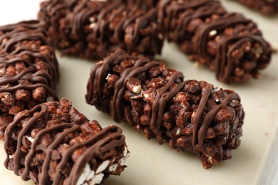 Delicious chocolate puffed rice bars on white wooden table, closeup