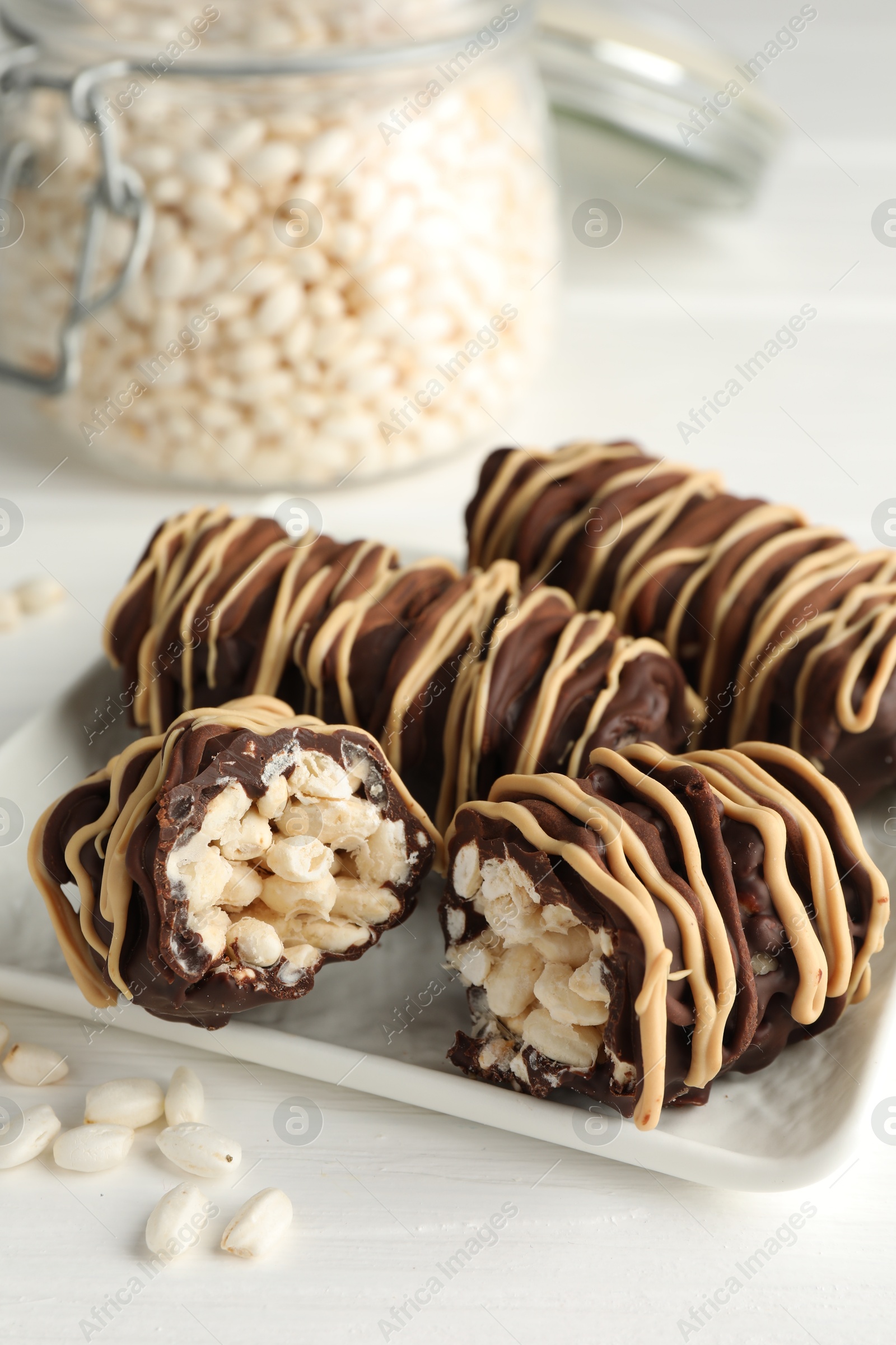 Photo of Delicious chocolate puffed rice bars on white wooden table, closeup