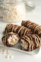 Delicious chocolate puffed rice bars on white wooden table, closeup