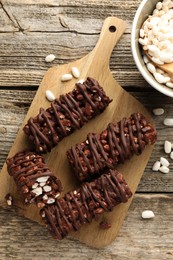 Delicious chocolate puffed rice bars on wooden table, flat lay