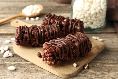 Delicious chocolate puffed rice bars on wooden table, closeup