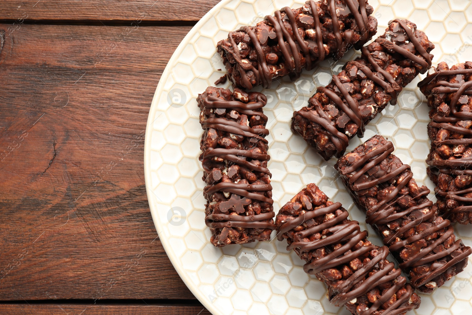 Photo of Delicious chocolate puffed rice bars on wooden table, top view. Space for text