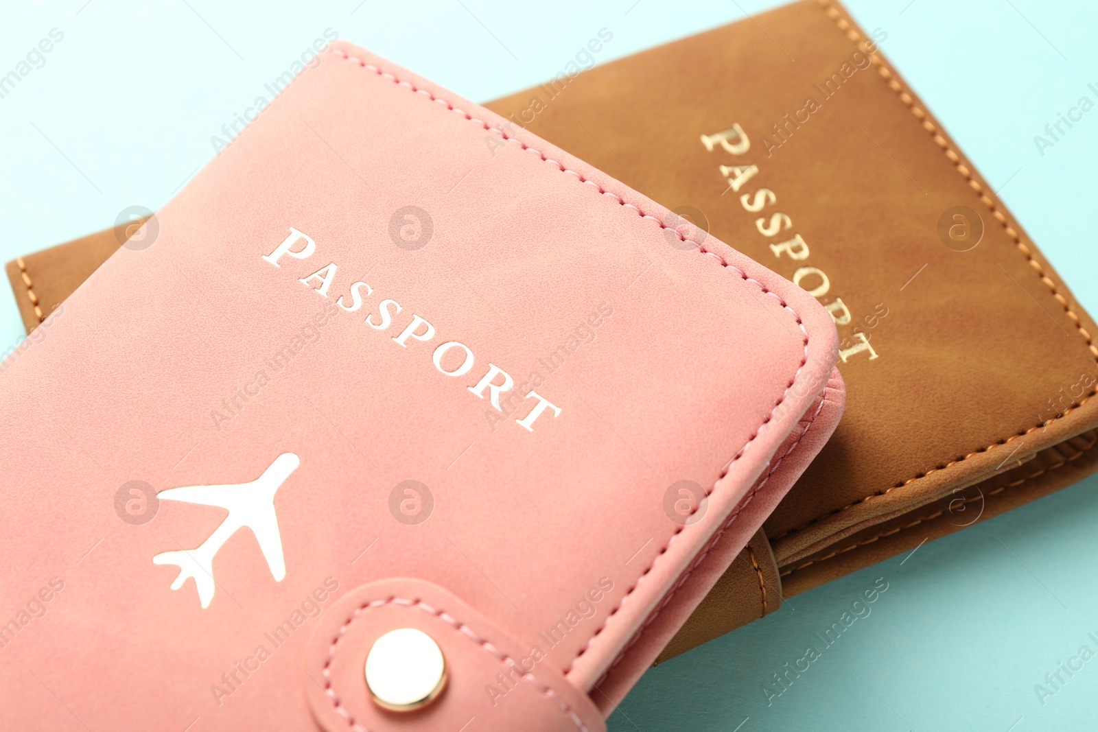 Photo of Two passports in bright covers on turquoise background, closeup