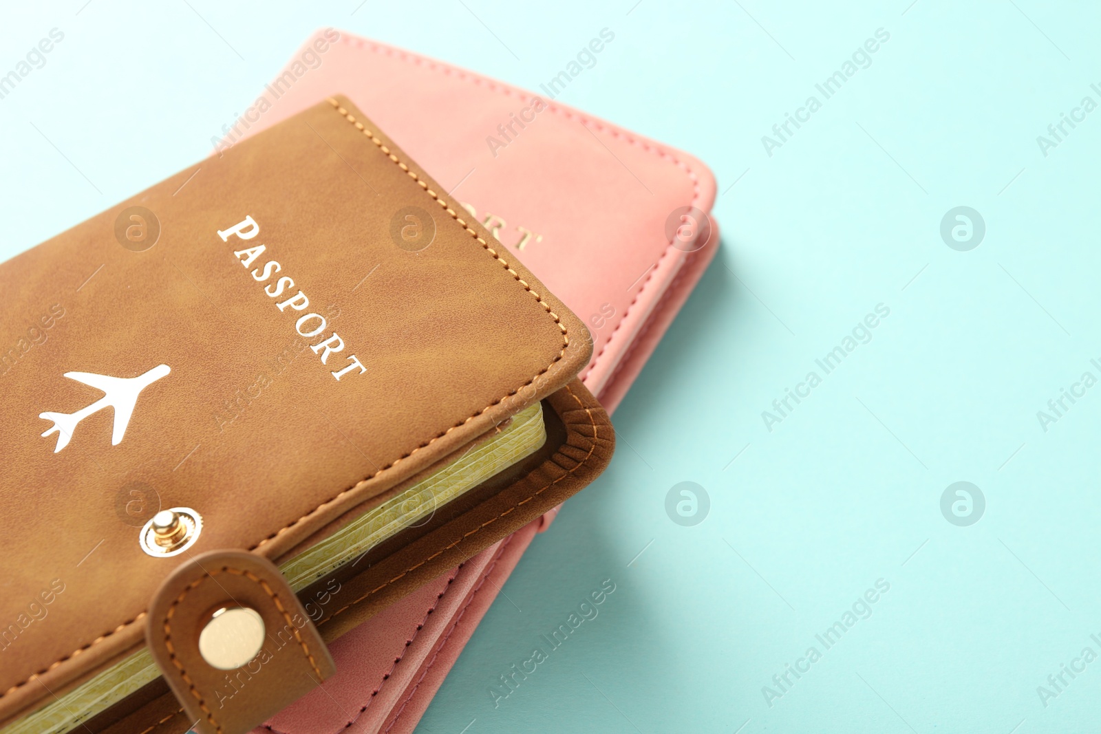 Photo of Two passports in bright covers on turquoise background, closeup. Space for text